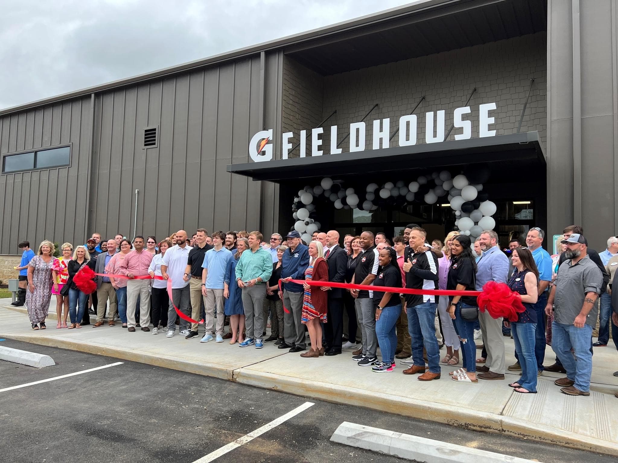 Community ribbon-cutting ceremony at the front entrance of The Gatorade Fieldhouse — neighbors, families, partners, and local officials marking the opening.