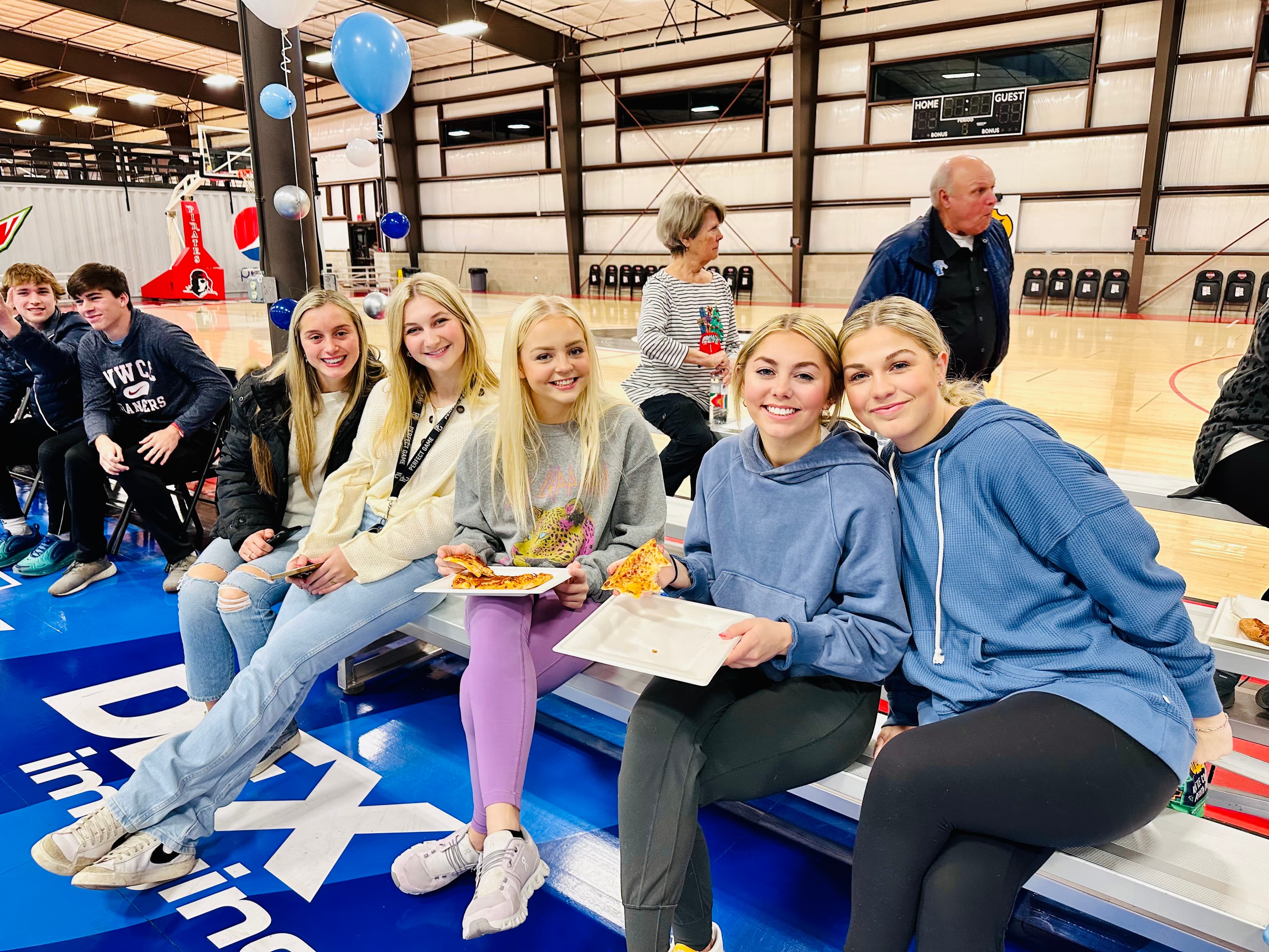 Friends courtside with pizza at a birthday party on the hardwood