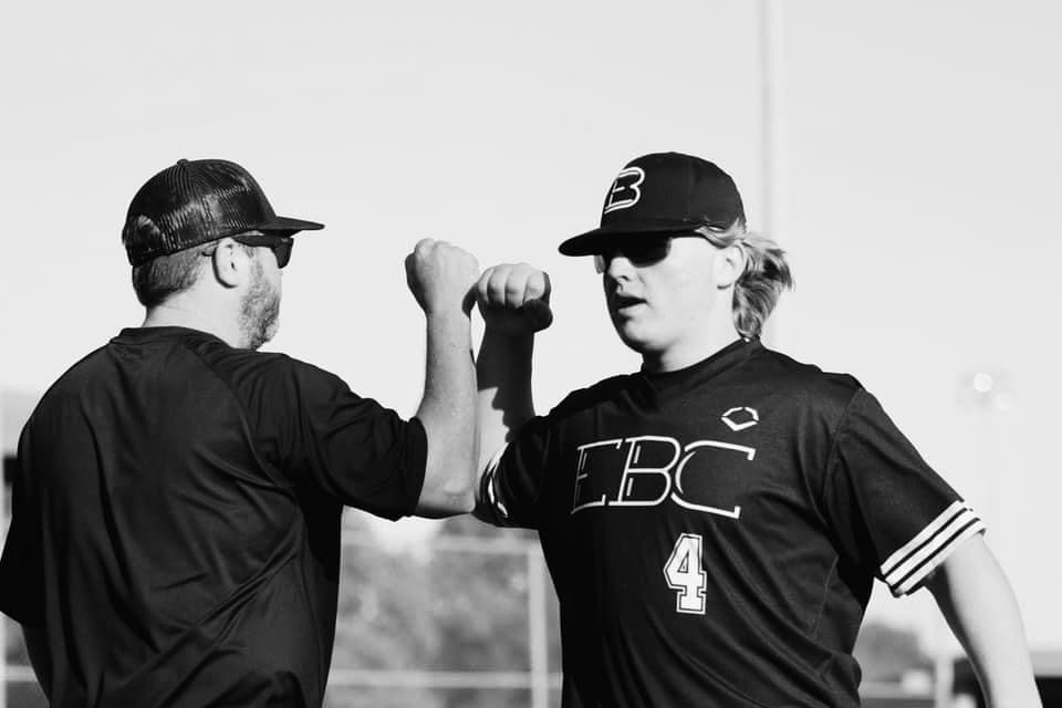 Coach and player share a fist bump on the diamond