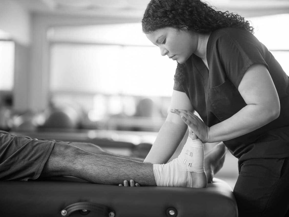 Sports medicine clinician taping an athlete's ankle